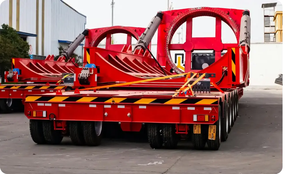 Overmaatse industriële machines beveiligd op een zware platte trailer in een commercieel transportterrein.